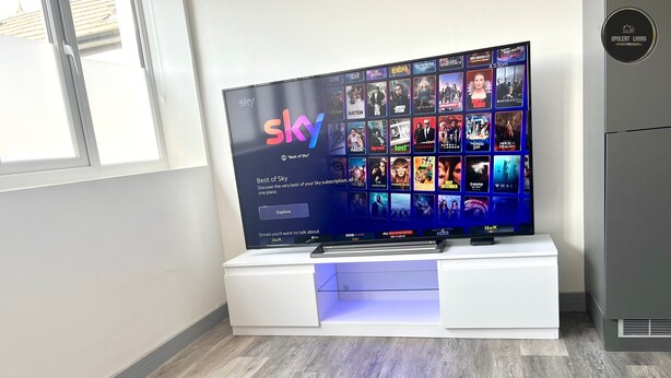 Un téléviseur à écran plat, posé sur un meuble blanc, avec l’interface d’abonnement Sky.