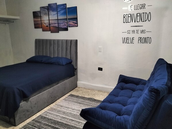 A bedroom with a bed, a sofa, and a wall with a welcome message.