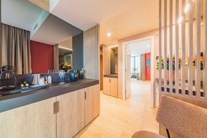Una cocina moderna con armarios de madera, una encimera negra y diversos electrodomésticos. Hay un comedor con una silla de madera y una mesa.