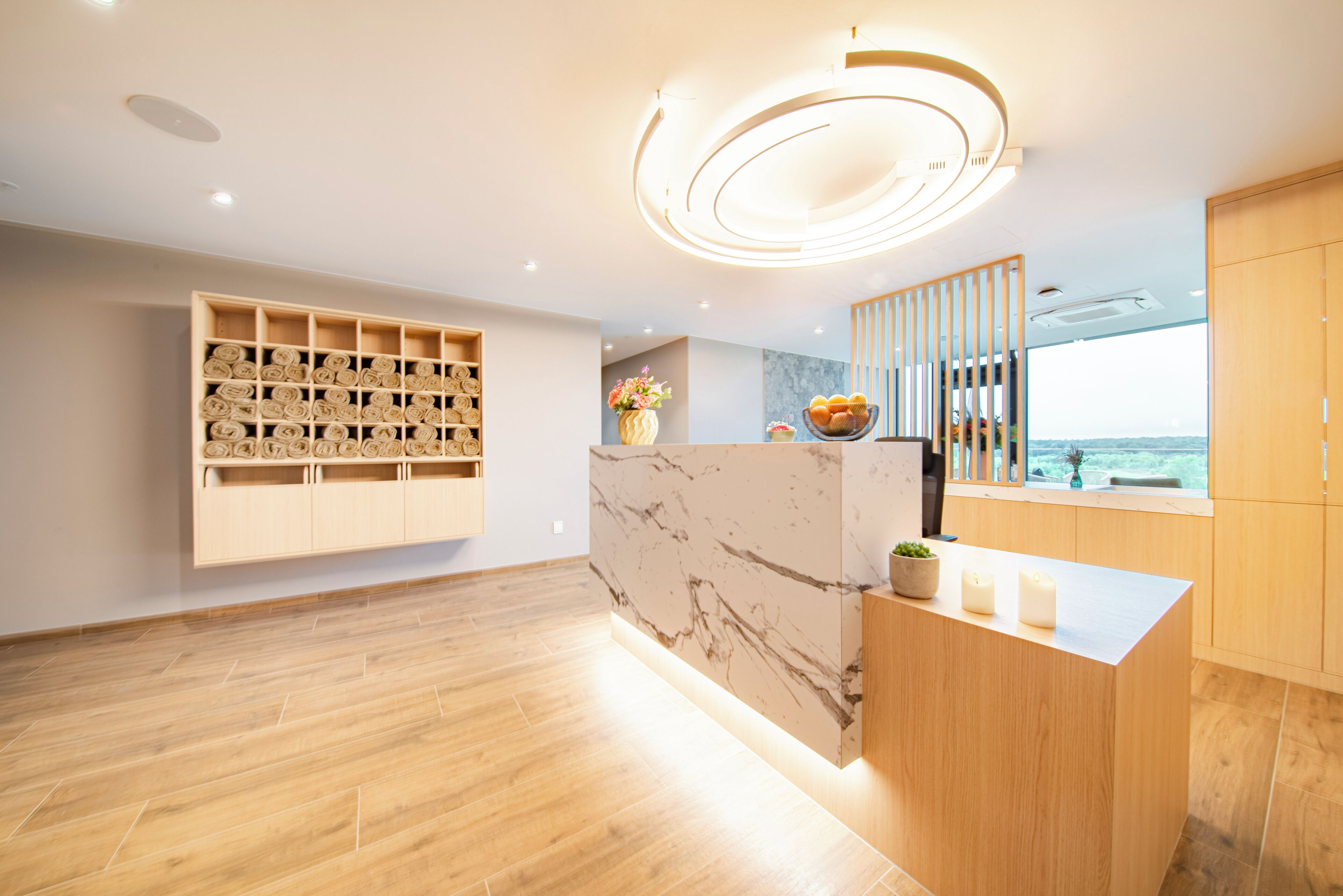 A modern kitchen with wooden cabinets, a marble backsplash, and a built-in shelf with towels.
