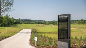 Un sendero pavimentado que conduce a un campo de golf con un panel de exhibición digital.