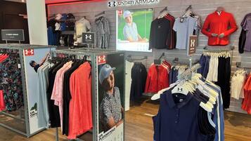 Una tienda de ropa con la marca Under Armour, que exhibe diversa ropa deportiva y de uso diario.