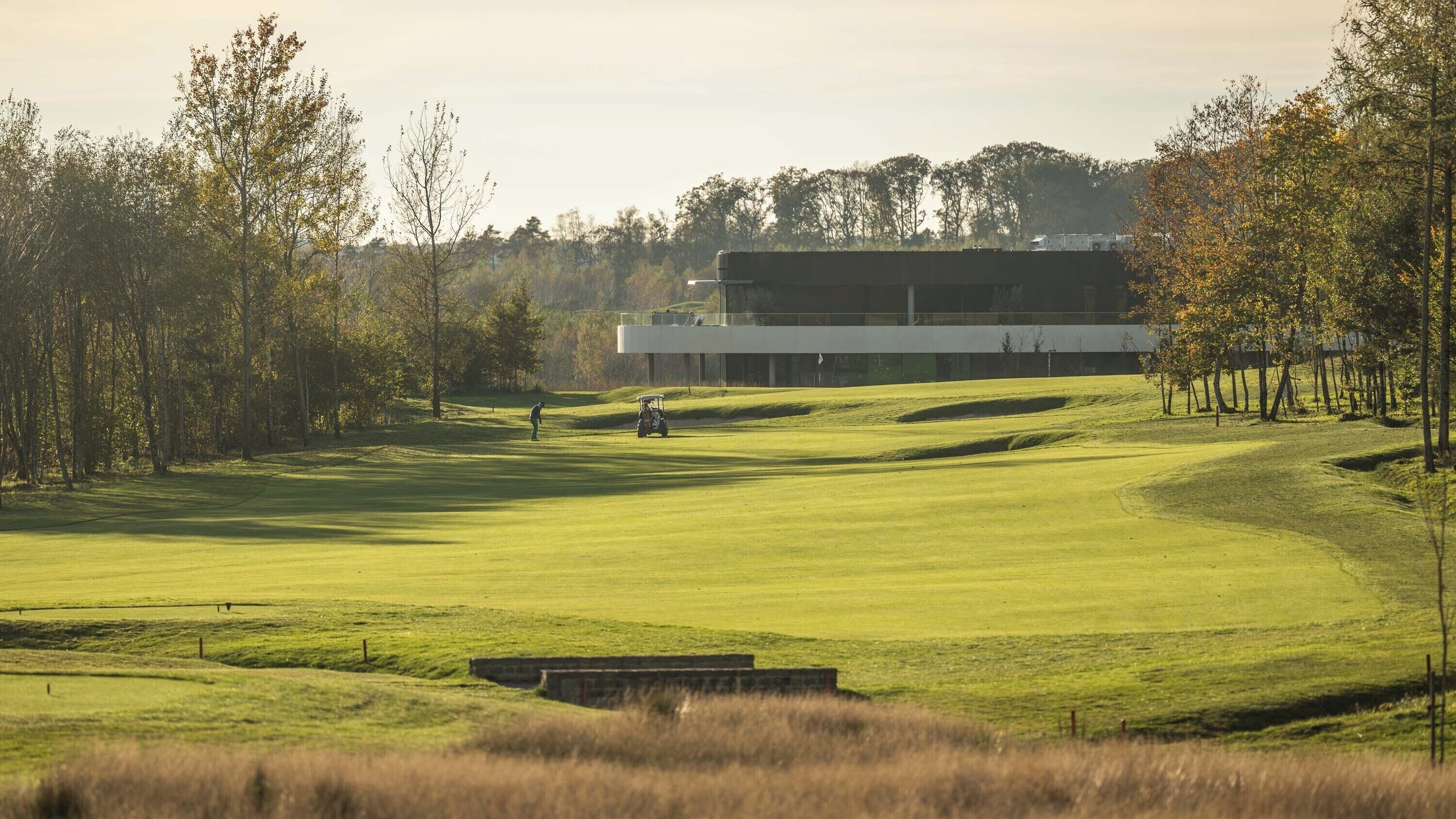 A golf course with a modern building in the background.