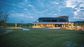 Un bâtiment moderne doté d’un toit incurvé, entouré d’une zone verdoyante et d’arbres.