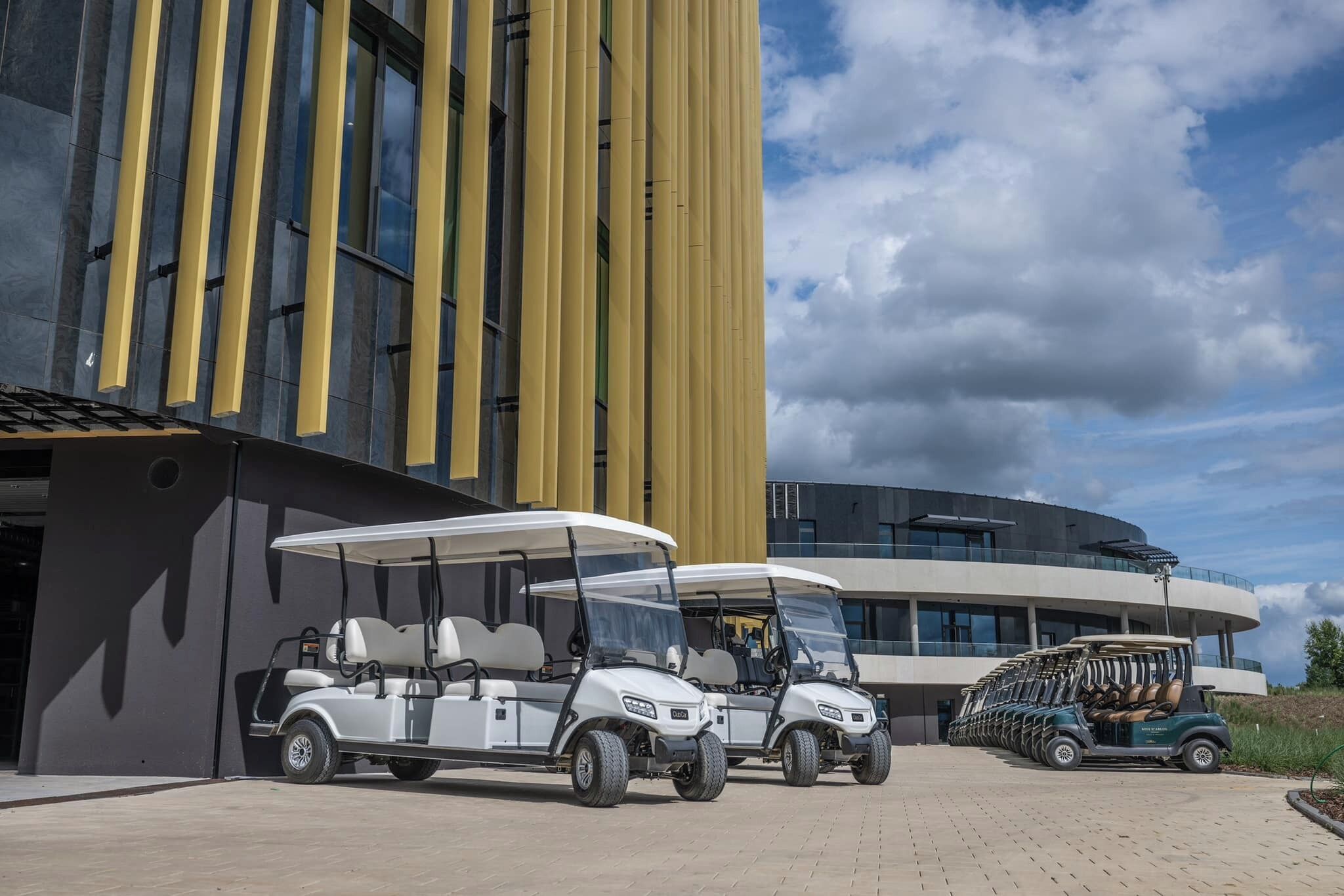A modern building with a curved facade and a golf cart parked in front.