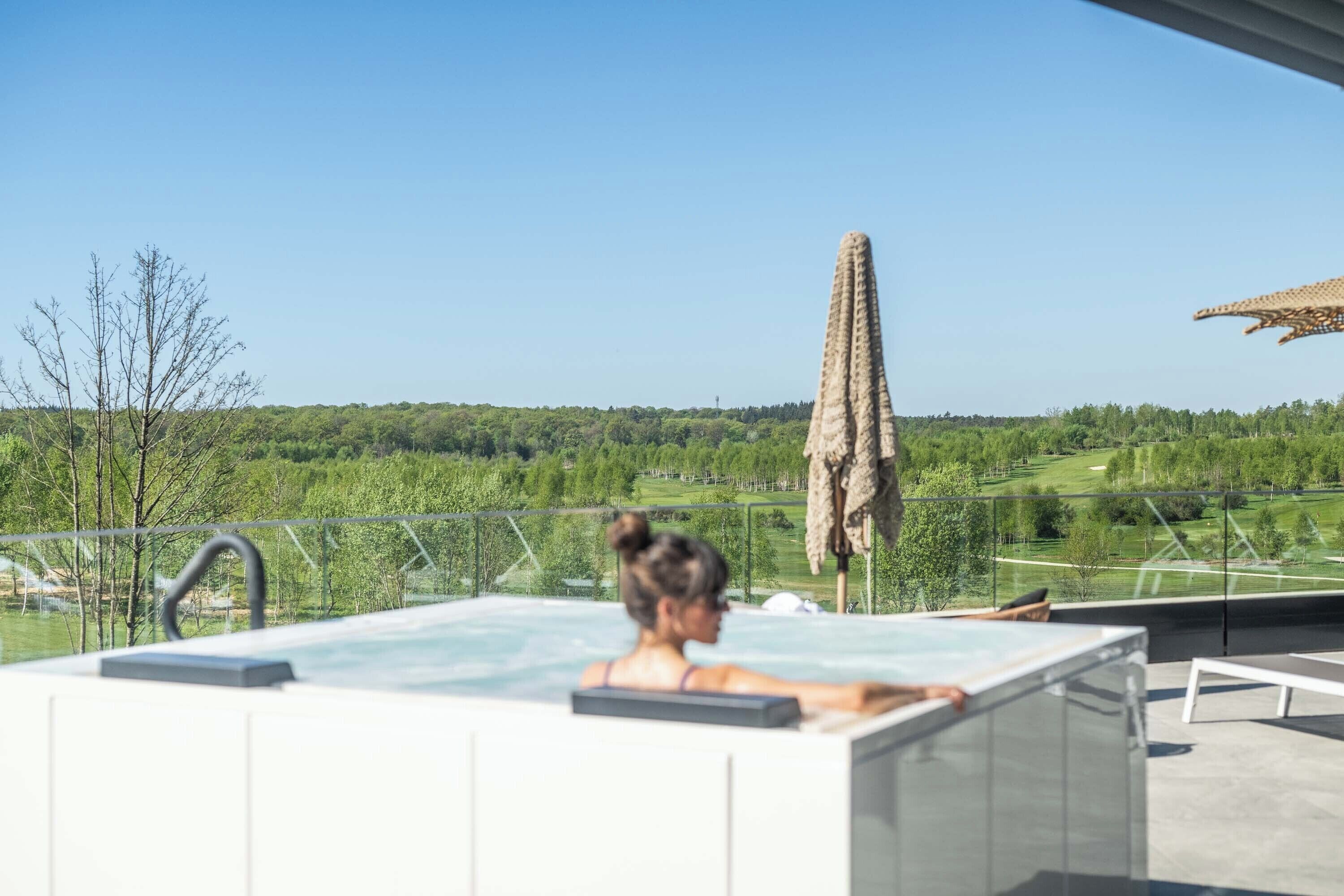 A spa area with a hot tub, lounge chairs, and a view of a green landscape.