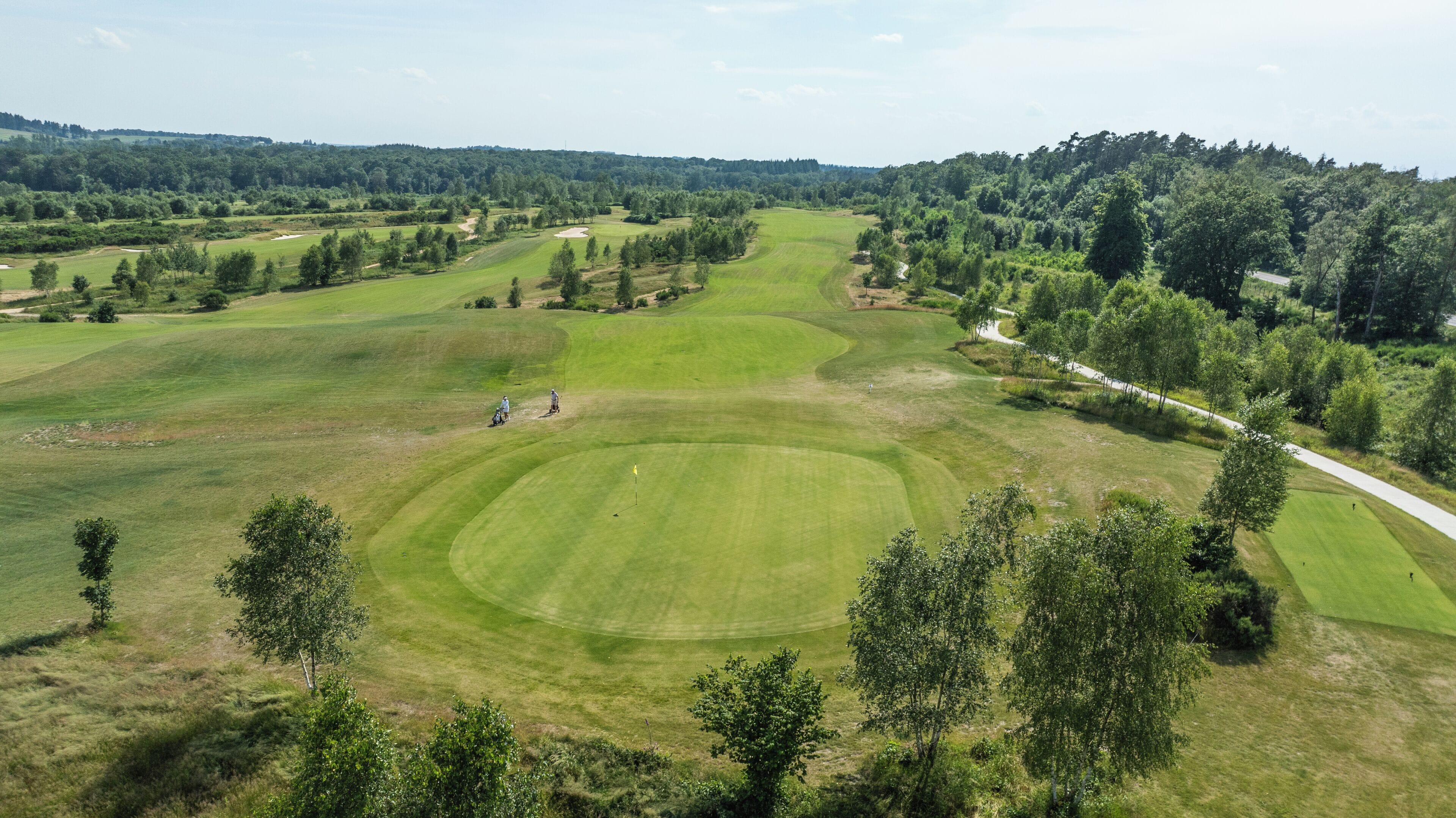 Un parcours de golf doté de plusieurs allées, de bunkers de sable et d’une zone boisée.