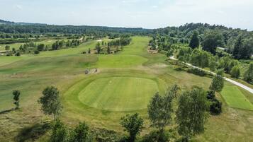 Un campo de golf con varios calles de juego, trampas de arena y una zona boscosa.