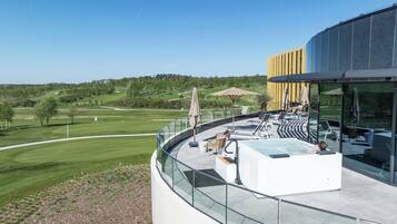 Un bâtiment moderne doté d’un balcon en verre donnant sur un terrain de golf.
