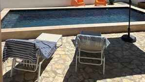 Un espace piscine comprenant deux chaises longues, un parasol et une vue sur le paysage.