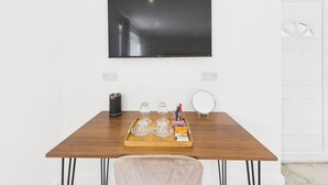 Una habitación moderna con una mesa de madera, un objeto cilíndrico negro y una bandeja con vasos y un paquete de comida.