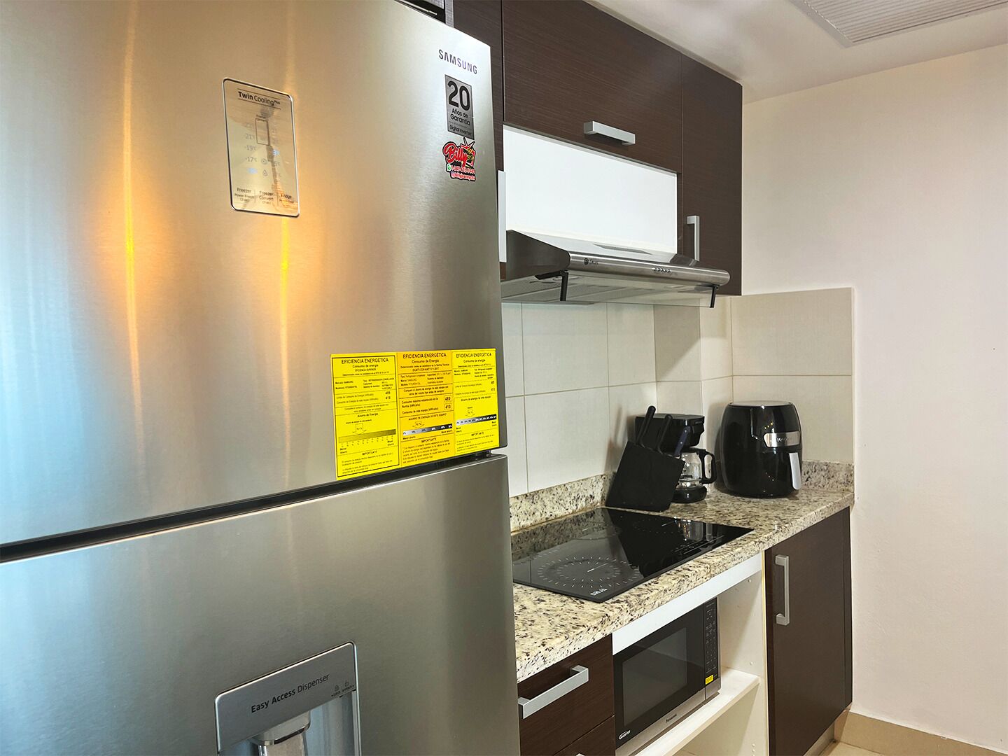 A kitchen with a stainless steel refrigerator, a microwave, a coffee maker, and a toaster.