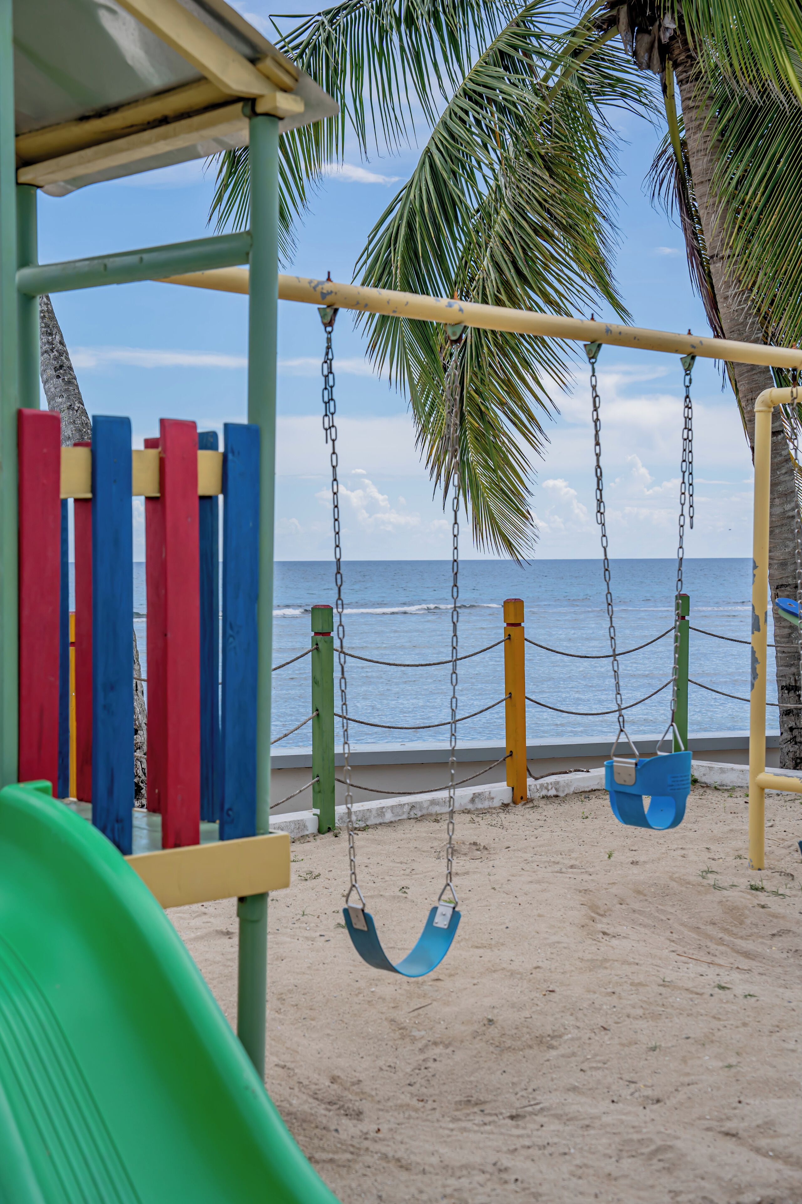 Ein Strandspielplatz mit Schaukeln und einer Rutsche mit Blick auf den Ozean.
