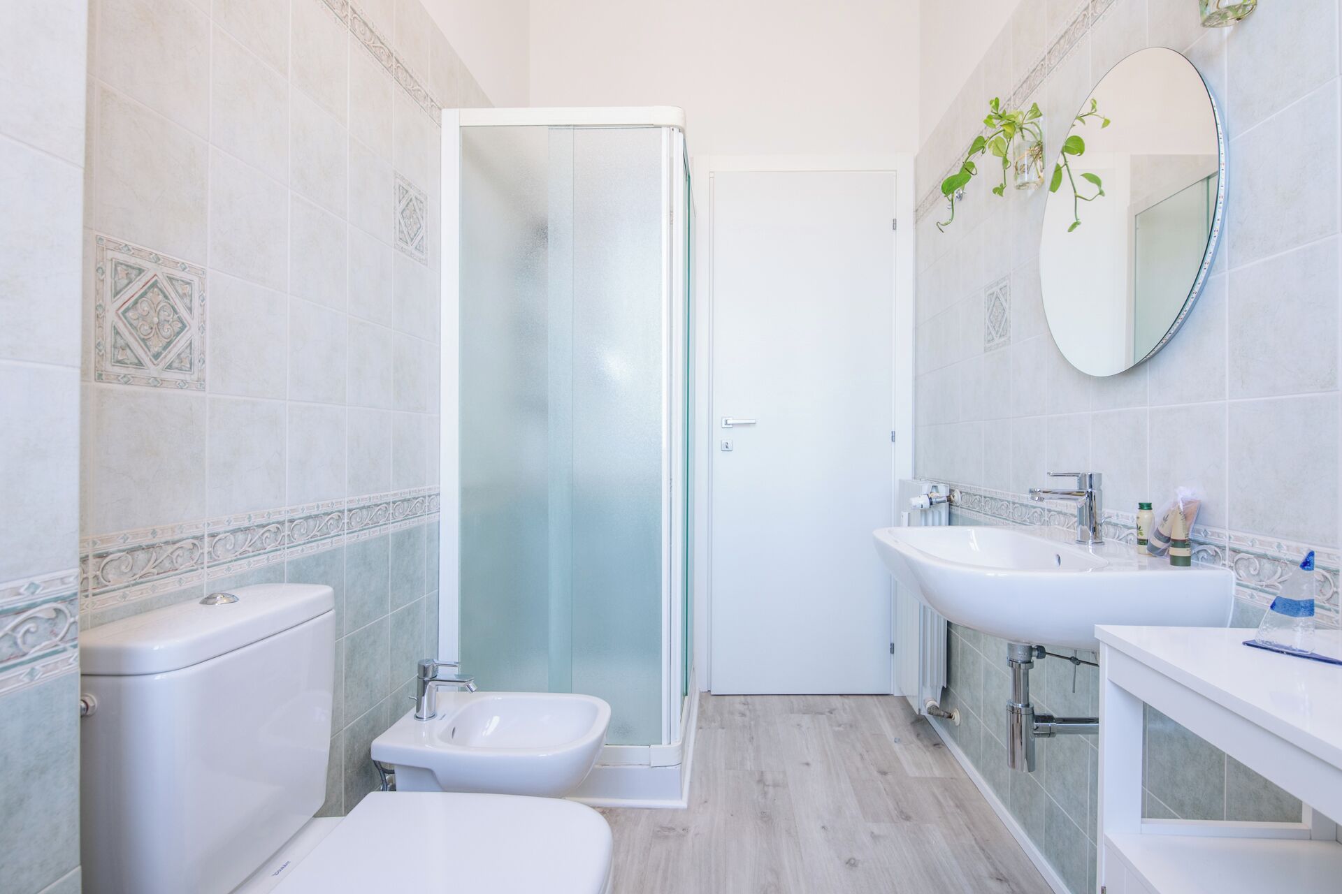 A modern bathroom with a glass shower enclosure, a toilet, a bidet, and a sink.