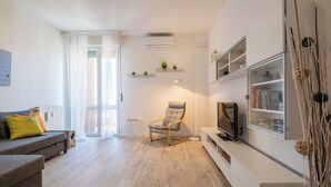 Un salon moderne avec un canapé, un fauteuil, un téléviseur et une bibliothèque.