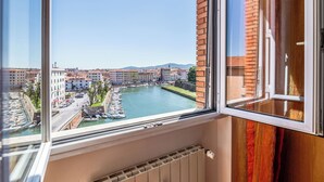 Une vue depuis une fenêtre donnant sur une rivière, avec des bâtiments et un ciel dégagé.