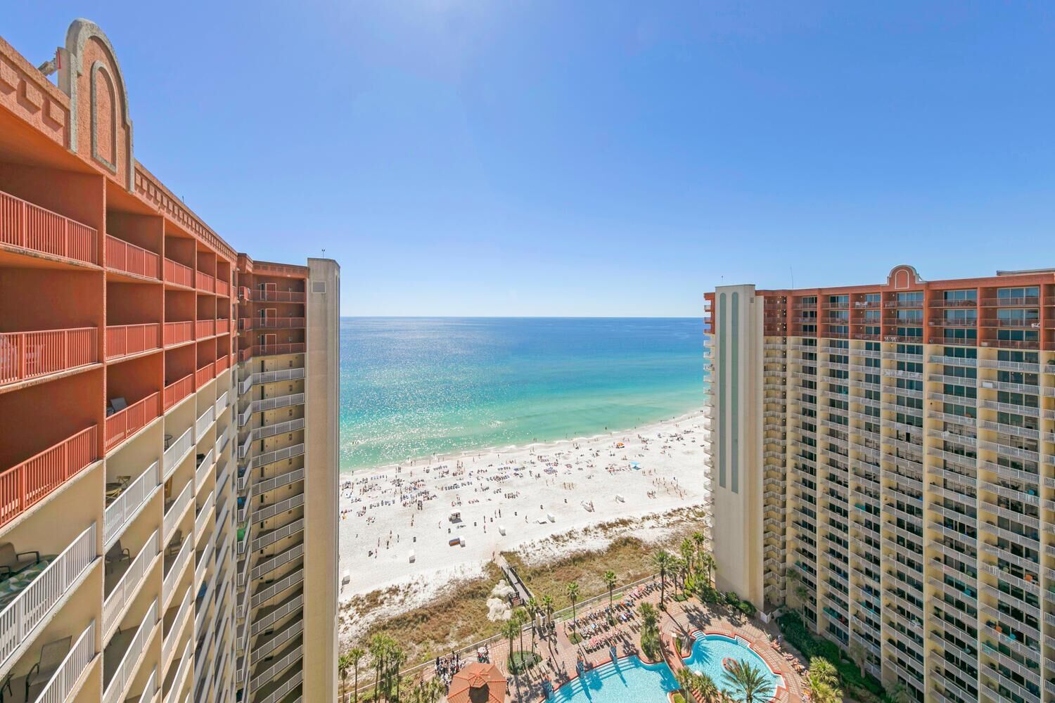 A high-rise hotel with a beach view, multiple balconies, and a swimming pool.
