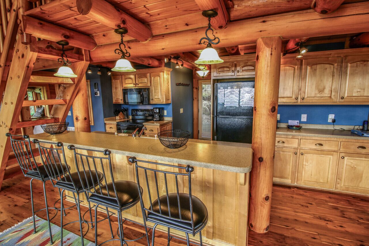 Une cuisine rustique avec des meubles en bois, un îlot central doté de tabourets de bar et des luminaires suspendus.