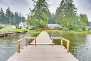 A wooden dock leading to a calm lake with houses and trees in the background. - Waterfront Grapeview Escape w/ Boat Dock & Views! (Grapeview)