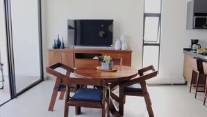 Une cuisine moderne avec un coin repas, comprenant une table et des chaises en bois, un téléviseur à écran plat et une machine à café.