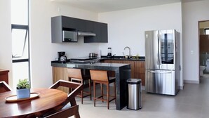 Une cuisine moderne dotée d’un îlot central, d’appareils électroménagers en acier inoxydable et de meubles de rangement en bois.