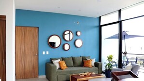 Un salon moderne avec un mur bleu, une porte en bois et un canapé agrémenté de coussins.