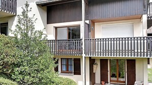 En tvåvåningsbyggnad med balkonger, stora fönster och krukväxter.