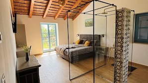 Un dormitorio con separador de vidrio, vigas de madera en el techo y una cama, con vistas al exterior.