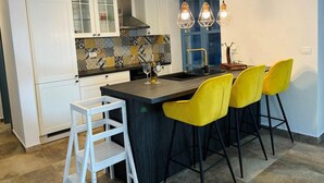 Una cocina moderna con armarios blancos, encimera negra y taburetes amarillos.