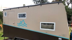 Un grande camper con esterno marrone e beige, due finestre e un motivo a onda blu sul lato.