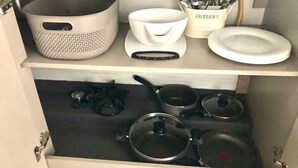 Un pensile da cucina con pentole, padelle, un tagliere, una ciotola e un portautensili.