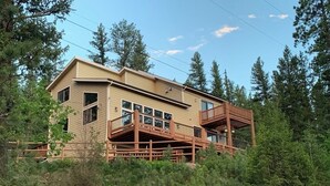 Eine zweistöckige Holzhütte mit Balkon, umgeben von dichtem Wald.