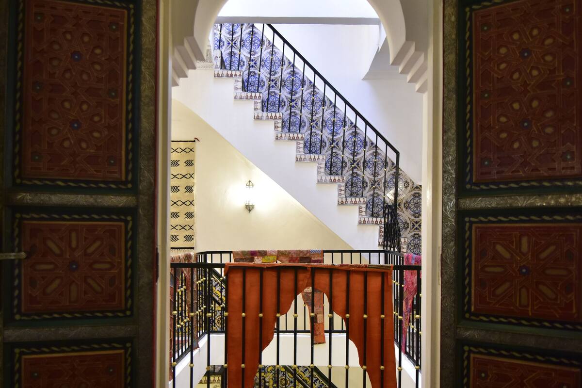 A staircase with ornate railings and a patterned carpet leading to a balcony.