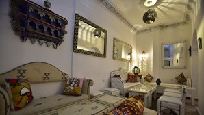 A traditional room with a sofa, a small table, and a chair. There are decorative mirrors and a hanging light fixture. - Zoco Riad (Tangier)