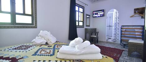 A hotel room with a bed, a television, a wardrobe, and a patterned rug.