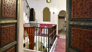 An interior view of a traditional building with a staircase, ornate doors, and patterned rugs. - Zoco Riad (Tangier)