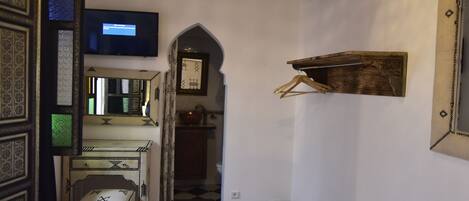 A room with a patterned carpet, a hanging light fixture, a television, and a mirror.