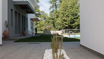 A modern building with a pool, outdoor seating, and a well-maintained garden.