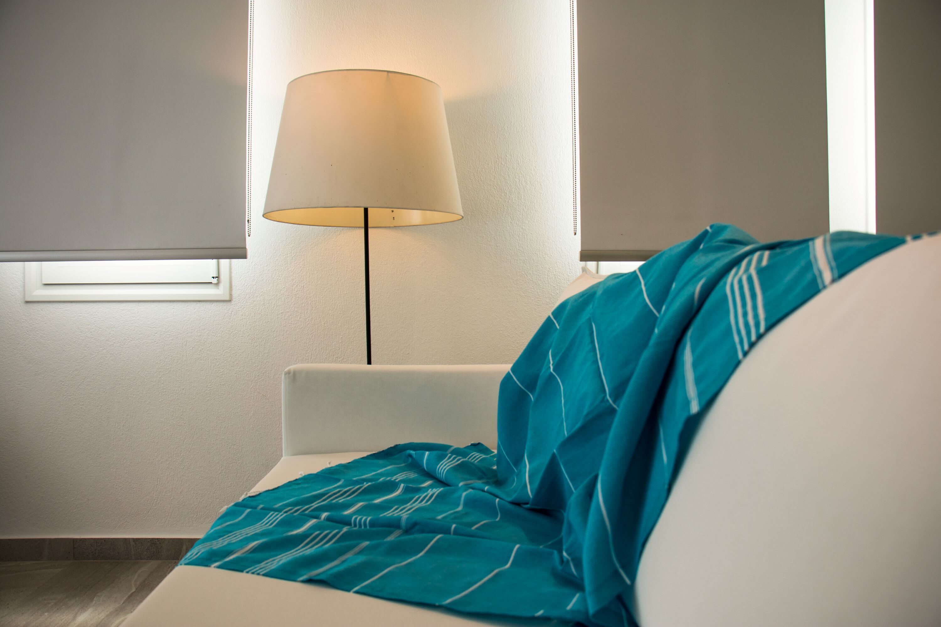 Una habitación de hotel con cama, lámpara y ventana con persianas.