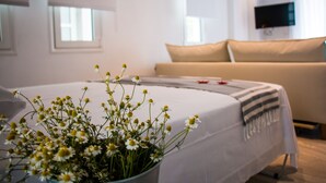 A hotel room with a bed, a TV mounted on the wall, and a window.