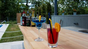 A bar area with a wooden countertop, various bottles, and glasses.