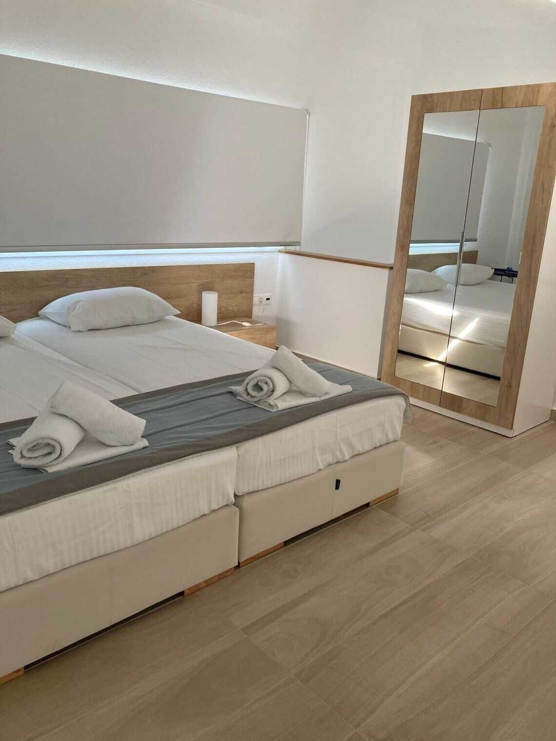 Un dormitorio moderno con una cama, una mesita de noche, un espejo y suelo de madera.