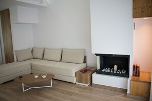 Ein modernes Wohnzimmer mit einem Ecksofa, einem Kamin, einem Couchtisch und einem kleinen Beistelltisch.