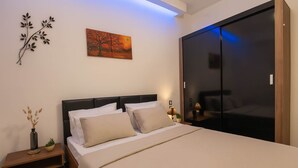 A bedroom with a bed, bedside tables, a nightstand, a wall-mounted artwork, and a sliding door closet.