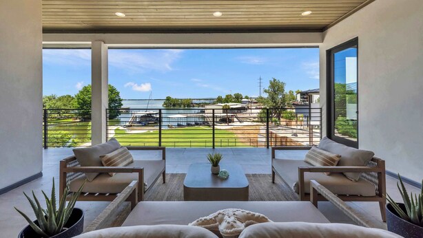 Een modern balkon met zitplaatsen en uitzicht op een jachthaven.