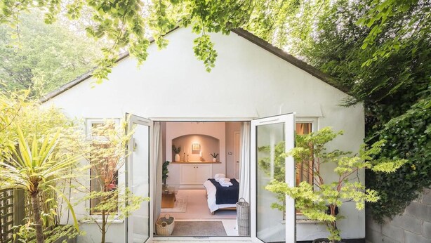 A small, private room with a bed, a window, and a door leading to a garden. - Cozy City Retreat in Bristol With Parking & Patio (Bristol)