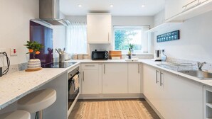 A modern kitchen with white cabinets, a built-in microwave, and a coffee menu sign. - Cozy City Retreat in Bristol With Parking & Patio (Bristol)