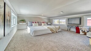A bedroom with a bed, a desk, a TV, and a window.
