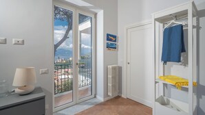 Ein Zimmer mit einer Schiebetür zum Balkon, einem weißen Heizkörper und einem weißen Kleiderschrank mit einem blauen sowie einem gelben Handtuch.