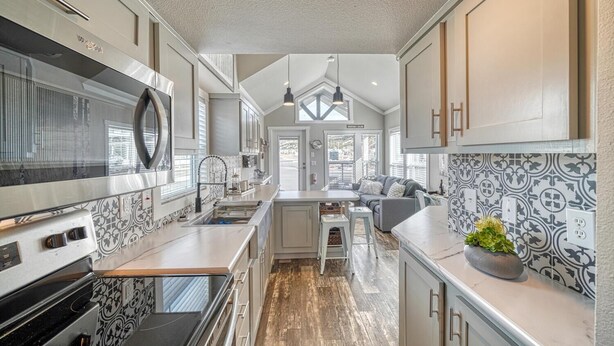Een moderne keuken met een centraal eiland, roestvrijstalen apparatuur en een decoratieve spatwand.